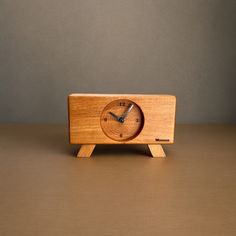 a small wooden clock sitting on top of a table next to a brown wall and floor