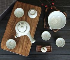 a tea set on a wooden tray with cups and saucers next to an empty cup