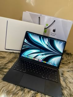 an open laptop computer sitting on top of a bed next to a box and other items