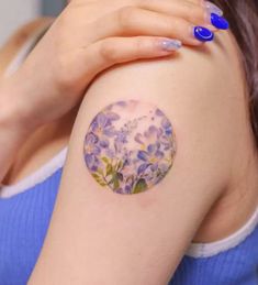 a woman's arm with a flowered circle tattoo on the left side of her arm