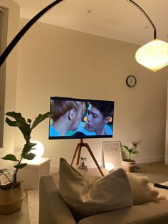 a flat screen tv sitting on top of a wooden stand in a living room next to a potted plant