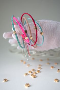 three bracelets are sitting on top of a white cloth and some gold beaded beads