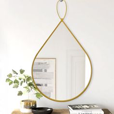 a mirror hanging from the side of a wall next to a table with books on it