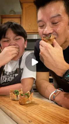 two people sitting at a kitchen counter eating food with chopsticks in front of them