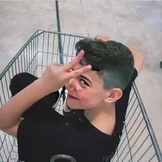 a young boy sitting in a shopping cart with his hand on the top of his head