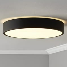 a circular light fixture hanging from the ceiling in a room with white walls and ceilings