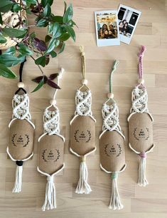 four small tassels hanging from twine on wooden floor next to potted plant