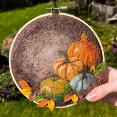 a hand holding up a small felt pumpkin decoration