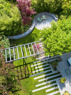 an aerial view of a garden with stairs leading up to the roof and trees in the background