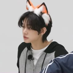 a man with black hair wearing an orange and white cat ears