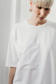 White cotton T-shirt with an ornamental, exaggerated pocket. Sleeves lowered and slightly longer than usual. Oversized in form.The neckline finished off with a binderColor: whiteFabric: 92% cotton, 8% elastane (produced in Poland) Wash in a washing machine in 30-40 degrees CelsiusThe model (176 cm) is wearing M/LSizes:XS/SBust: 114 cm Total length: 66 cmSleeve length: 33 cmM/LBust: 120 cm Total length: 68 cmSleeve length: 34 cm Oversized White Shirt With Pockets, Oversized Tops With Pockets And Shirttail Hem, White Cotton Tops With Pockets, White Summer Tops With Side Pockets, White Summer Top With Side Pockets, White Top With Pockets And Shirttail Hem, White Tops With Pockets And Shirttail Hem, Modern Cotton Tops With Side Pockets, Modern Relaxed Fit Tops With Pockets