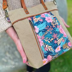 a woman is holding a purse with flowers on the front and side, in her hands