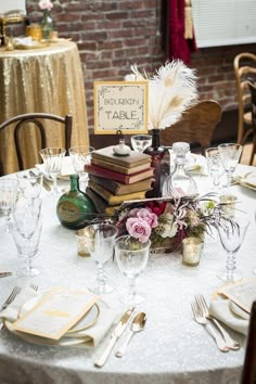 the table is set with books, wine glasses and place settings for guests to sit at