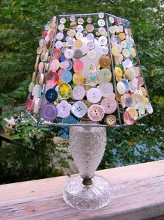 a lamp that has buttons on it sitting on a wooden table in front of some trees