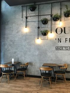 the interior of a restaurant with wooden tables and chairs, hanging planters on the wall