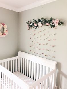 a white crib with flowers hanging on the wall