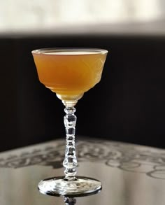 a glass filled with liquid sitting on top of a metal table next to a window