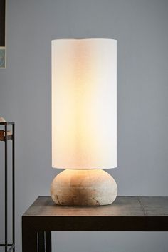 a table lamp sitting on top of a wooden table next to a white light shade