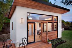 a small white house with wooden floors and windows on the outside, next to a deck