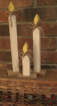 three candles with yellow birds on them sitting in front of a brick wall