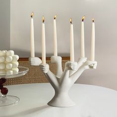 a white candle holder with five candles in it on a table next to a cake