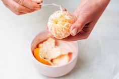 a person is holding an orange and eating it from a bowl with ice cream in it