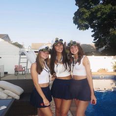 three young women in sailor outfits standing next to a swimming pool and posing for the camera