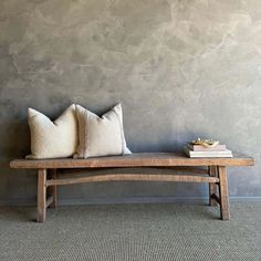 two pillows are sitting on a bench in front of a wall with a gray background