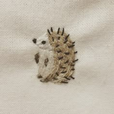 an embroidered hedgehog sitting on top of a piece of white fabric with black dots