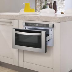 a kitchen with white cabinets and stainless steel microwave in the middle, open door on the right side