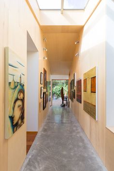 an empty hallway with paintings on the walls and people walking down one side in the distance