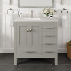 a bathroom vanity with a mirror above it and flowers in the vase on the counter