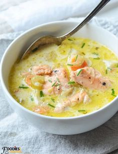 there is a bowl of soup with salmon in it and a spoon on the side