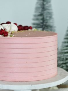 a pink frosted cake with cranberries and white icing on a table