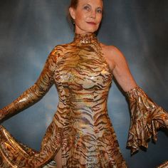 will fit size 5/6-9/10...5'6" or taller Be the envy of the dance floor with this stunning Gold Hologram Tango-Paso Doble Dress! Crafted of golden iridescent hologram tiger print lycra, this elegant ensemble boasts lots of flounces, a long sleeve with a peak at the wrist, and shimmering accents courtesy of volcano colored Swarovski rhinestones, which shine several different shades including purple & yellow. Make a statement with two thigh-high slits in the front, and show off your amazing tango Hologram Printing, Spanish Princess, Spanish Dress, Tango Dress, Your Amazing, Tiger Print, Dance Floor, The Dance, Volcano