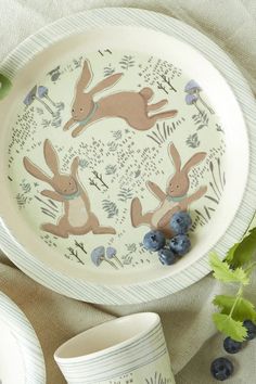 a plate with two rabbits on it next to blueberries and an eggplant