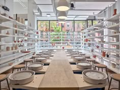 a long table with many plates on it in the middle of a room filled with shelves