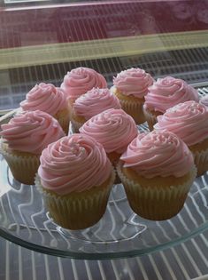 cupcakes with pink frosting sitting on a glass plate