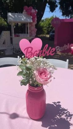 a pink mason jar filled with flowers and heart shaped cutout on top of a table