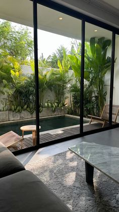 a living room with couches, tables and large glass doors leading to a pool