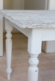 an old white table is sitting on the floor