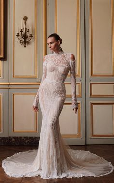 a woman in a white wedding dress standing on a wooden floor next to a chandelier