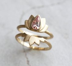 A part of our Zen collection, comes the second design with peach sapphire and brushed yellow gold setting, the Lotus ring. The lotus flower is one of the most ancient and deepest symbols of our planet. The lotus flower grows in muddy water and rises above the surface to bloom with remarkable beauty. Untouched by the impurity, lotus symbolizes the purity of heart and mind. The lotus flower represents long life, health, honor and good luck. This ring and ring set is original design patented Capuci Kibbe Jewelry, Pear Sapphire Ring, Classic Kibbe, Unique Sapphire Rings, Sapphire Wedding Ring Set, Peach Sapphire Rings, Diamond Alternative Engagement Ring, Peach Sapphire Engagement Ring, Sapphire Engagement Ring Set