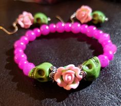 two bracelets with pink and green beads, one has a flower on the end