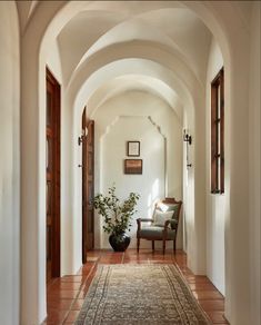 an archway leading to a living room with a chair and potted plant on the floor