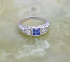 Vintage 18K White Gold Art Deco Sapphire and Diamond Ring, 4mm square central fine blue sapphire, round diamond, side stones, pierced filigree top, Ring size 6, Circa 1930, weight 2.14 grams Stock # BB140R08 This listing contains photographs of the actual item you will receive. Our items are in excellent condition with little or no signs of wear and many are one of a kind pre-owned estate finds. Please look closely at the pictures in this listing as they are part of the product description. Plea Antique Blue Platinum Jewelry, Antique Blue Diamond Jewelry, Art Deco Blue Jewelry With Single Cut Diamonds, Blue Art Deco Jewelry With Single Cut Diamonds, Blue Jewelry With Single Cut Diamonds For Anniversary, Blue Single Cut Diamond Jewelry For Anniversary, Princess Cut Blue Platinum Jewelry, Blue Princess Cut Platinum Jewelry, Vintage Blue Ring With Single Cut Diamonds