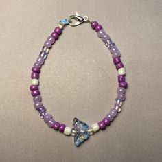 Elevate your ensemble with our Whimsical Butterfly Purple Beaded Bracelet. Handcrafted with care, this charming piece features an assortment of purple beads in various shades, complemented by delicate white pearl-colored beads for an added touch of elegance. At its heart, a delightful butterfly-shaped bead in clear blue and purple tones steals the spotlight, infusing the bracelet with a whimsical allure. Available in two lengths: 18cm and 20cm, this bracelet offers versatility and comfort for everyday wear. Whether worn as a personal statement or gifted to a loved one, our Whimsical Butterfly Purple Beaded Bracelet brings a playful pop of color and style to any outfit. This was also inspired by the K-Pop group BTS and their beautiful song Butterfly Bohemian Purple Bracelets With Heart Beads, Purple Tiny Beads Beaded Bracelets As Gift, Lavender Bracelets With Colorful Beads, Adjustable Purple Beaded Bracelets With Heart Beads, Purple Heart Beaded Bracelets, Adjustable Purple Beaded Necklace With Heart Beads, Purple Pearl Bracelet Gift, Gift Purple Pearl Bracelet With Round Beads, Purple Pearl Bracelet With Round Beads As Gift