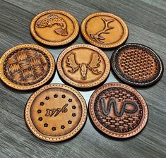 six leather coasters with different designs on them sitting on top of a wooden table