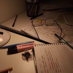 a desk with some pens and glasses on top of it next to a computer mouse