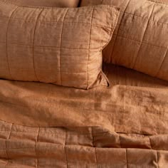 a close up of a bed with brown sheets and pillow cases on top of it